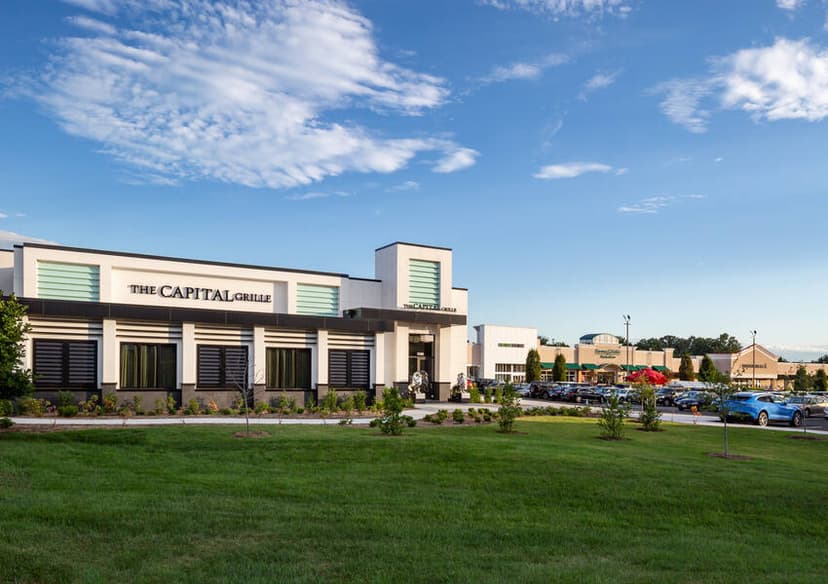 The Capital Grille restaurant exterior with cars parked in a vibrant, green landscape.